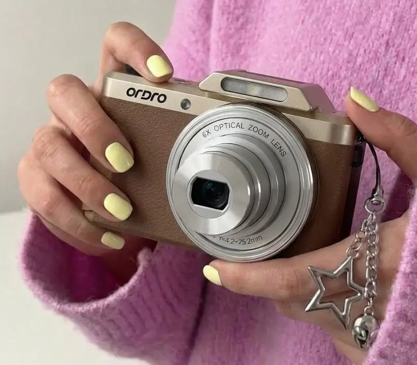 ORDRO D27 Y2K digital camera in gold and brown, held by a creator, showcasing its retro aesthetic and compact design for everyday photography.